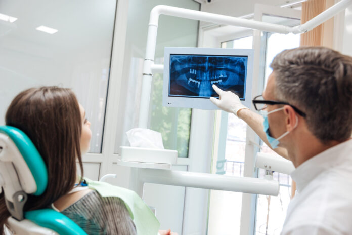 Male dentist shows a patient x-ray of teeth